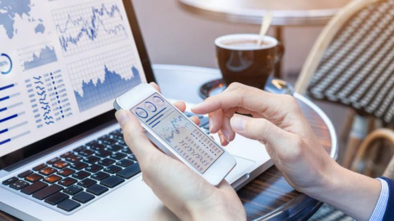 Image of person checking their shares portfolio on mobile phone and computer